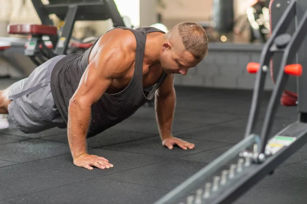Şınav çeken genç sporcu. Spor salonunda egzersiz yapan kaslı ve güçlü bir adam. Spor kıyafetli genç yakışıklı bir adamın spor salonunda şınav çekmesi..