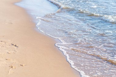 Kumlu sahilde denizin yumuşak dalgası. Odaklanma, bulanık görüntü. Boşluğu kopyala.