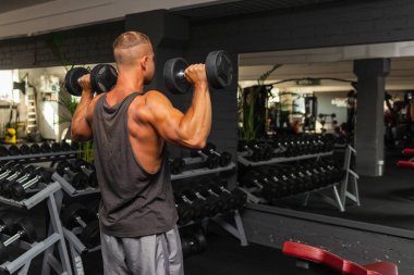 Spor salonunda aptal gibi egzersiz yapan genç ve formda bir adam. Sağlıklı bir adam aptallarla çalışıyor. Kapalı alanda çekim yapıyor..