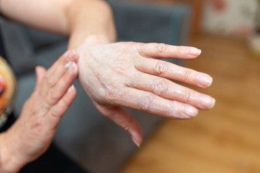 Kadının elleri cildine nemlendirici sürüyordu. Evde kadın el kremi sürmüş, yakından. Gençlik ve cilt esnekliği için bırakılmış kozmetik kremi olan eller. Kişisel bakım. minimalizm kavramı.