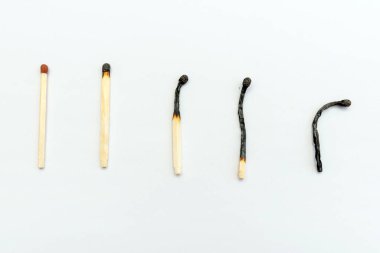 Bir sıra yanmış kibrit ve beyaz arka plan, üst manzara, yakın çekim. İnsan yaşamının aşamaları kavramları veya insan yaşamının farklı aşamaları kavramları. Seçmeli odaklanma.