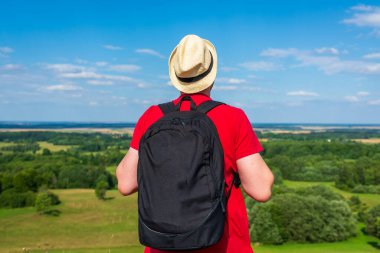 Orman manzarasına hayran olan genç bir adam. Arka planda vahşi ormanla birlikte yaz günü tek başına ayakta duran genç bir adam. Seyahat yaşam tarzı kavramı arka görünümü