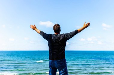 Kafkasyalı adam kollarını açıp okyanusu izliyor. Kollarını uzatmış mutlu bir adam. Yaz günü kollarını dikiz aynasından kaldırmış bir adam..