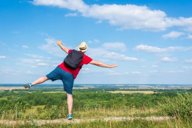 Orman manzarasına hayran olan genç bir adam. Arka planda vahşi ormanla birlikte yaz günü tek başına ayakta duran genç bir adam. Seyahat yaşam tarzı kavramı arka görünümü