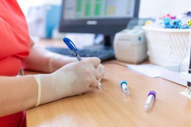 Bulanık bir arka planda laboratuvar kliniğinde test tüplerine yazı yazan bilim adamı..