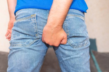 Man holding his butt in pain.The pain caused by hemorrhoid.Man is at home.