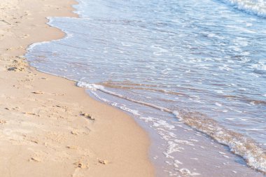 Kumlu sahilde denizin yumuşak dalgası. Odaklanma, bulanık görüntü. Boşluğu kopyala.