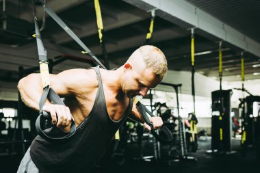 Spor salonunda egzersiz yapan kaslı bir adam, spor salonunda triseps egzersizi yapan. Güçlü çıplak erkek karın kası. Yakışıklı vücut geliştirici. Spor salonunda spor yapıyor..