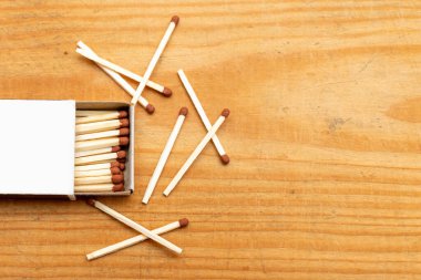 Ahşap arka planda kutuda kibrit var. Yakın plan çekim. Açık kibrit kutusundaki kibrit çöpleri düz katmanlarda. Açık kibrit kutusundaki kibrit kutusuyla eşleşir. Seçili odak noktası. Boşluğu kopyala.