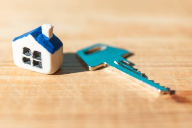 Ahşap arka planda ev anahtarı olan minyatür yeni bir ev, emlak ve emlak işi kavramı. Kapalı, seçici odaklı..