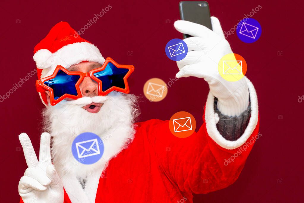 Santa Claus getting attention on social media. Santa Claus using different social media E-mail services on his phone.Red studio background.