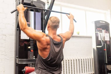 Spor salonunda egzersiz yapan kaslı bir adam, spor salonunda triseps egzersizi yapan. Güçlü çıplak erkek karın kası. Yakışıklı vücut geliştirici. Spor salonunda kapalı alanda çalışıyor..