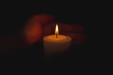 Bir avuç içi mum yangınıyla gece ilgilenir. Seçici odak, koyu siyah arkaplan. Yaklaş..