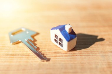 Ahşap arka planda ev anahtarı olan minyatür yeni bir ev, emlak ve emlak işi kavramı. Kapalı, seçici odaklı..