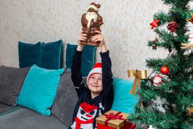 Kanepede oturan çocuk hediyesini kaldırıyor Noel Baba 'nın hediyeleri, elinde hediyeler..