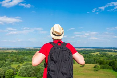 Orman manzarasına hayran olan genç bir adam. Arka planda vahşi ormanla birlikte yaz günü tek başına ayakta duran genç bir adam. Seyahat yaşam tarzı kavramı arka görünümü