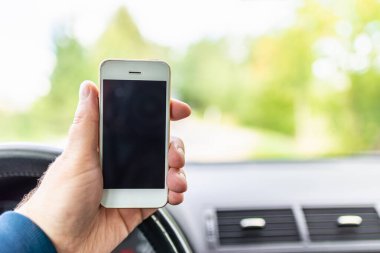 Erkekler el ele tutuşur ve ekrandaki akıllı telefona dokunur, otoyolda bulanıklaşır. Yazın arka planda. Kopya alanı, reklam, afiş, model..