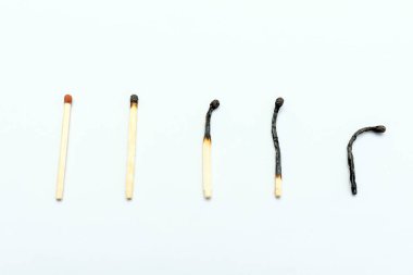 Bir sıra yanmış kibrit ve beyaz arka plan, üst manzara, yakın çekim. İnsan yaşamının aşamaları kavramları veya insan yaşamının farklı aşamaları kavramları. Seçmeli odaklanma.