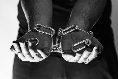 Zincirli insan elleri bir hapishanede dışarı çıkıyor. Gri duvar. Odaklan..