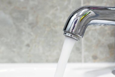 Pahalı su krom lüks bir musluktan akıyor, yakın plan..