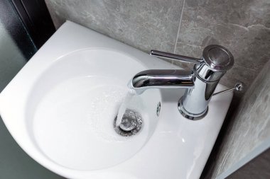 Beyaz seramik lavaboya akan modern tasarım krom su musluğu. Yukarıdan görüntüle.