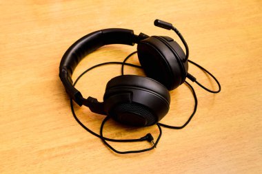 Masanın üstünde mikrofon olan siyah oyun kulaklığı..