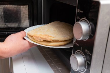 İşlenmemiş fast food mikrodalgaya konurken çocuğun eline koyulan sağlıksız, küçük, dondurulmuş pizza. Sağlıksız yemek, fast food, abur cubur konsepti.