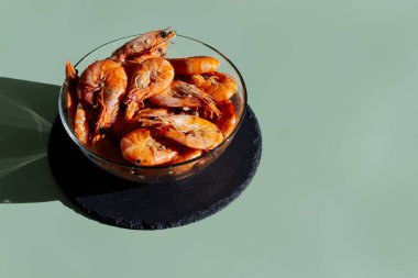 Zeytin arka planında şeffaf bir kasede karides. Kral karidesleri zeytin grisi arka planda.