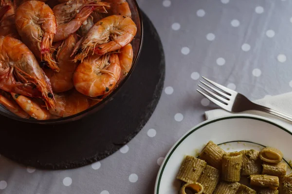 Shrimps in a bowl.Dinner table.Pasta with pesto sauce.