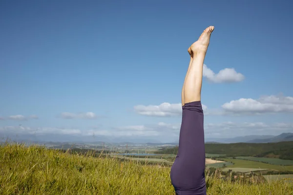 A woman in purple leggings against a background of mountains.Yoga time