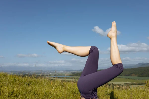 A woman in purple leggings against a background of mountains.Yoga time