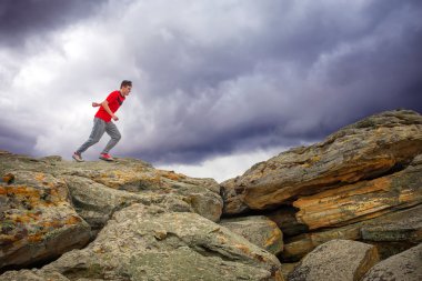 Çalışan, kayalar dağ bölgesinde üstünden atlayarak sporcu. 