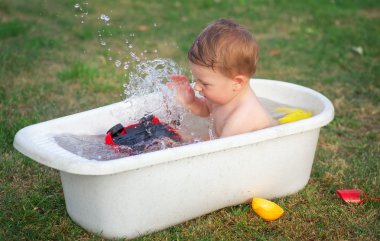 Küçük bir bebek banyo banyo ve oyuncak araba ile oynama.