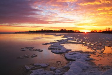 Günbatımı ateşli gökyüzü ve donmuş gölün güzel kış manzarası