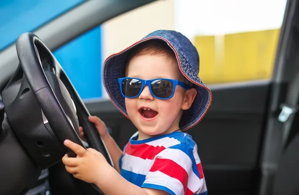 Joyeux petit garçon mignon avec des lunettes assis dans la voiture — Photo