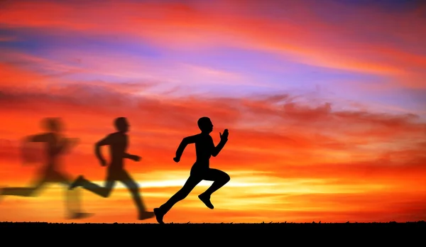 Silhouette di correre l'uomo contro il cielo colorato . — Foto Stock