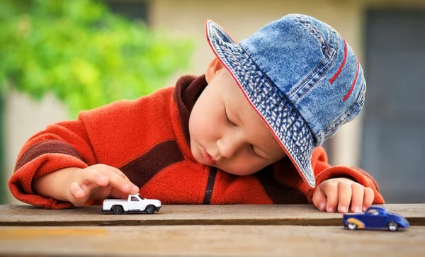 Little boy plays with colorful toy cars.