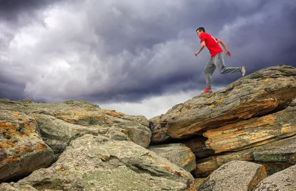 Мужчина бегает, прыгает через скалы в горной местности . — стоковое фото