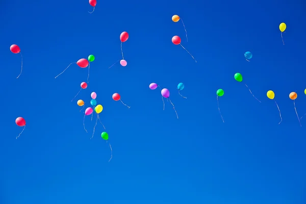 Un sacco di palloncini colorati che volano sul cielo blu — Foto Stock