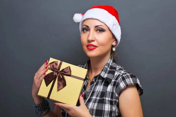 Belle fille dans la tête de Père Noël avec boîte cadeau sur fond gris . — Photo