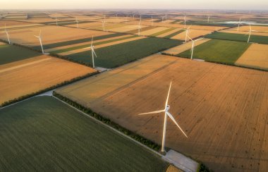 Yenilenebilir yel değirmenlerinin hava görüntüsü, ekolojik enerji sağlayan türbinler. Denizin yanındaki geniş tarım çayırlarında esen rüzgardan enerji alıyorlar. Alternatif elektrik