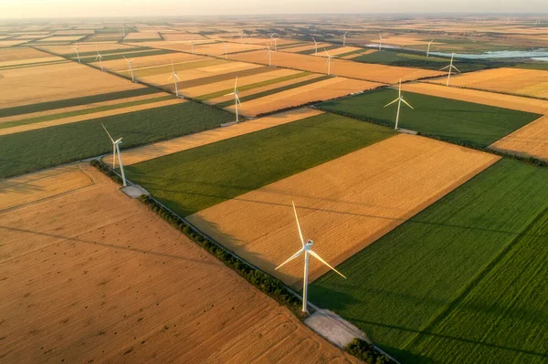 Yenilenebilir yel değirmenlerinin hava görüntüsü, ekolojik enerji sağlayan türbinler. Denizin yanındaki geniş tarım çayırlarında esen rüzgardan enerji alıyorlar. Alternatif elektrik