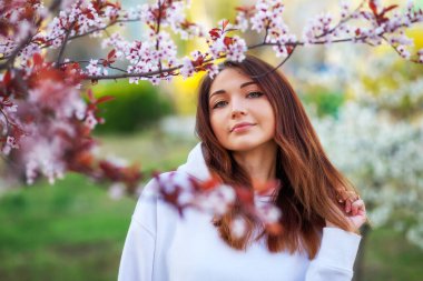 Gün batımında şeftali ağacının yanında duran gülümseyen güzel kız. Gülen surat. Bahar geldi..