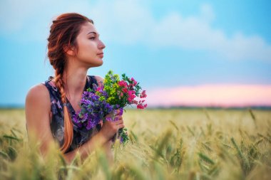 Güzel kız doğanın tadını çıkarıyor. Bahar Sahasında giyinmiş güzel bir genç kız.