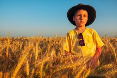 Buğday tarlasında şapkalı bir çocuk. Altın çavdar, buğday. Yaz