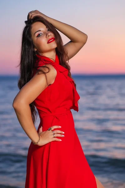 Menina Morena Bonita Vestido Vermelho Posando Praia Durante Nascer Pôr — Fotografia de Stock