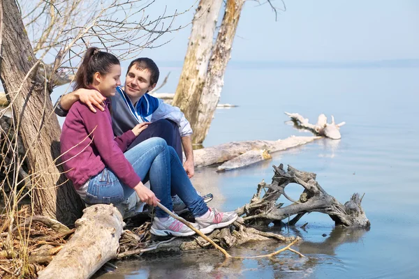 Lovers sitting on a snag ot the coast and looking at each other. — Stock Photo, Image