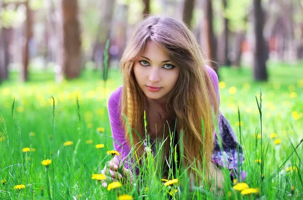 Güzel kız Sarı çiçekli çimlerin üzerine otur — Stok fotoğraf