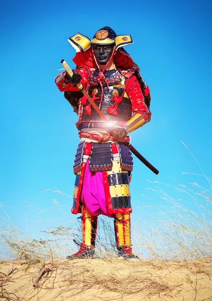 Ο άνθρωπος στο κοστούμι Σαμουράι βγάζει το ισχυρό ζεστό σπαθί. — Φωτογραφία Αρχείου