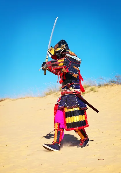 Homem em traje de samurai com espada correndo na areia . — Fotografia de Stock